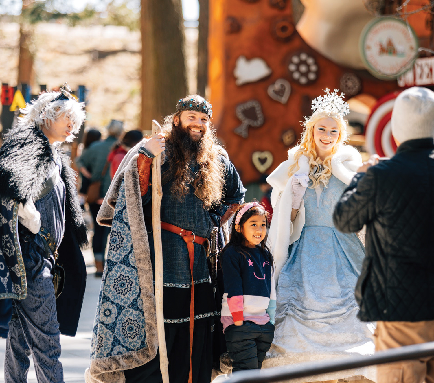 A young girl poses for a photo with costumed characters.