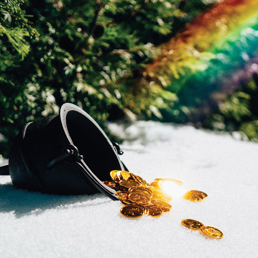 Gold coins spilling out of a black cauldron with a rainbow.